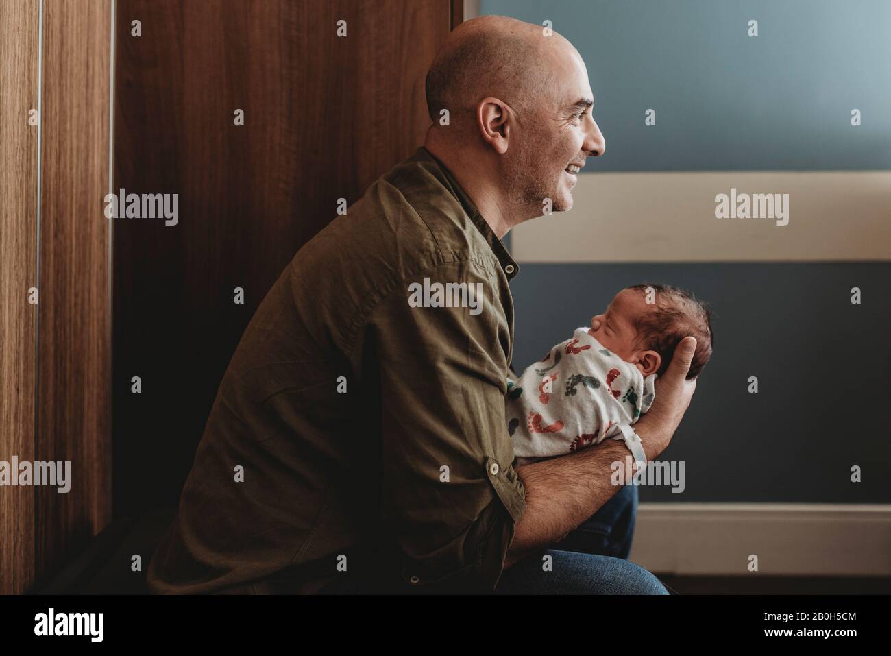 Side view of happy father holding newborn son in hospital Stock Photo