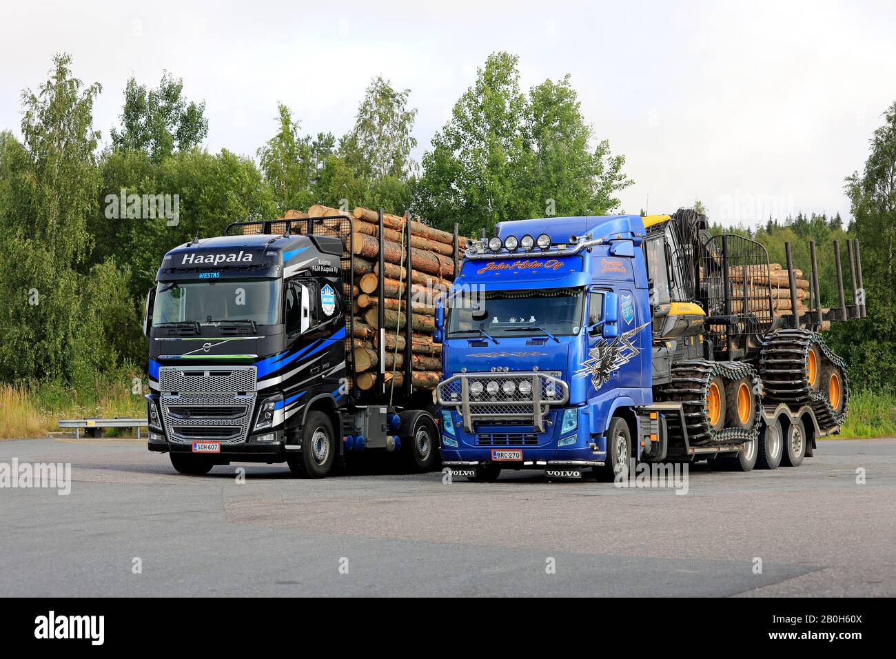 Volvo FH trucks of Haapala pulling a log load and of Juha Holm Oy pulling Ponsse forest machinery, parked side by side. Humppila, Finland. Aug 8, 2019 Stock Photo