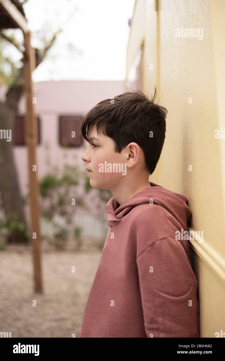 Portrait of a teenage boy leaning against wall looking away Stock Photo