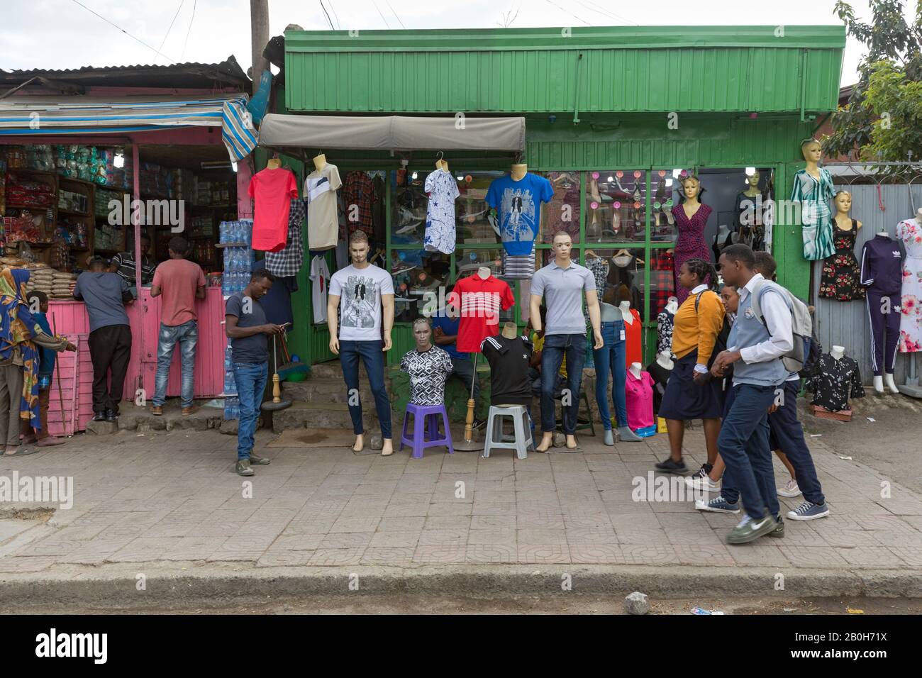 01.11.2019, Addis Ababa, Addis Ababa, Ethiopia - Students in school uniforms are walking in front of a clothing store. Dressed mannequins stand and ha Stock Photo