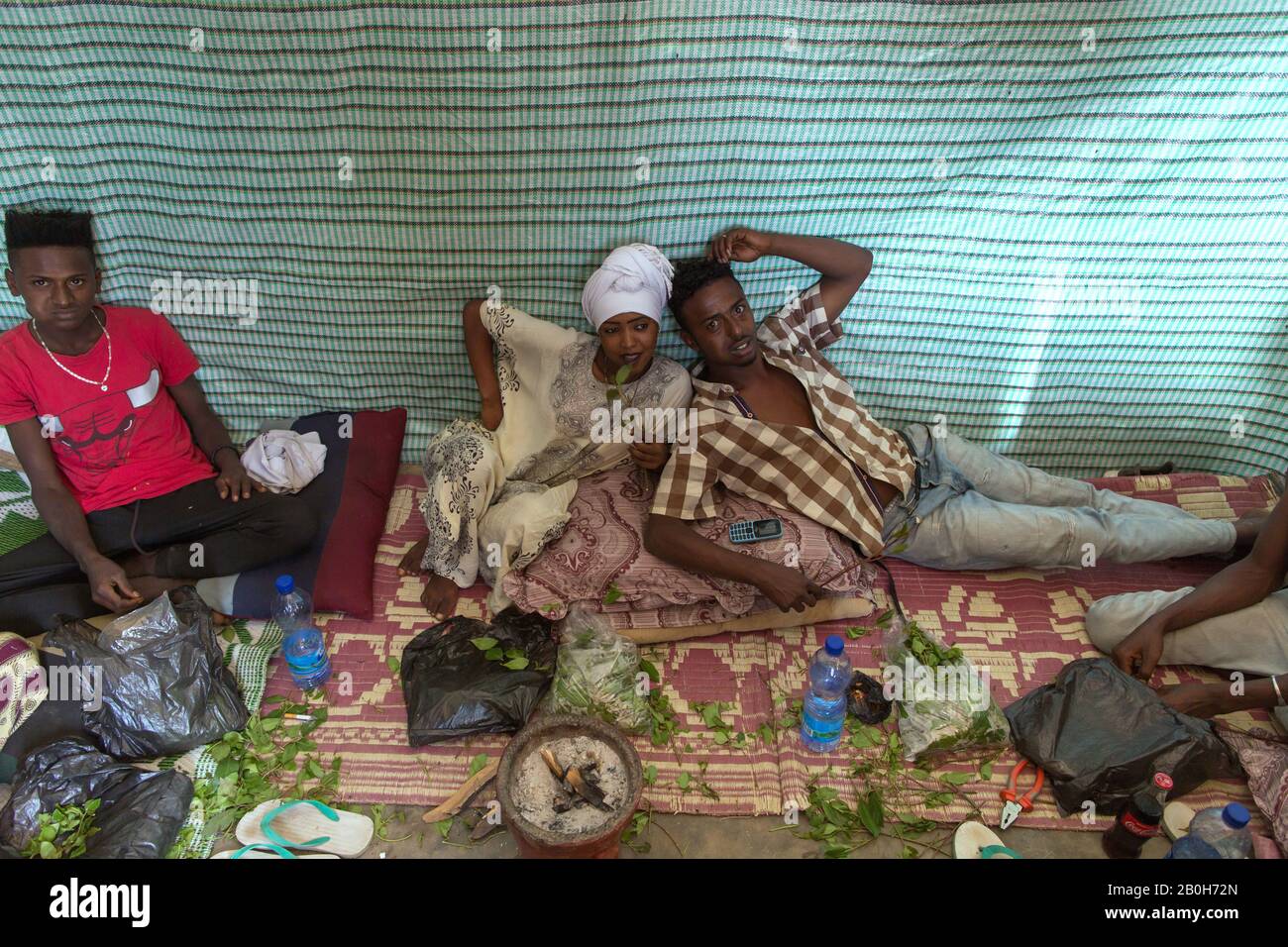 02.11.2019, Adama, Oromiyaa, Ethiopia - A woman and two men are sitting on the floor chewing khat. 8000 IDPs from the Somalia region live in four refu Stock Photo