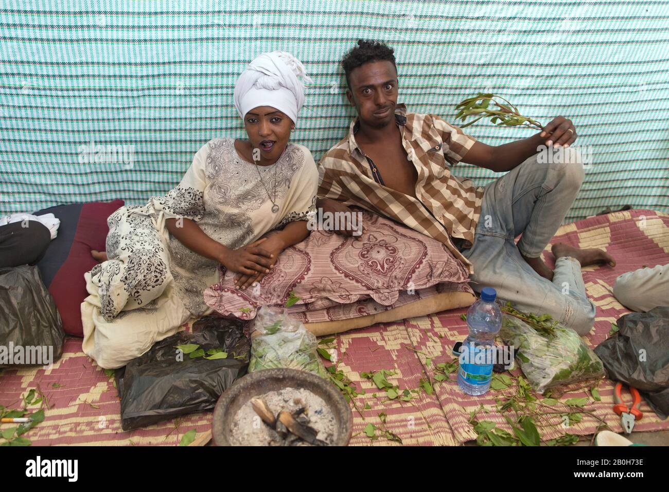 02.11.2019, Adama, Oromiyaa, Ethiopia - A woman and a man sit on the floor chewing khat. The man holds a khat branch. 8000 internally displaced person Stock Photo