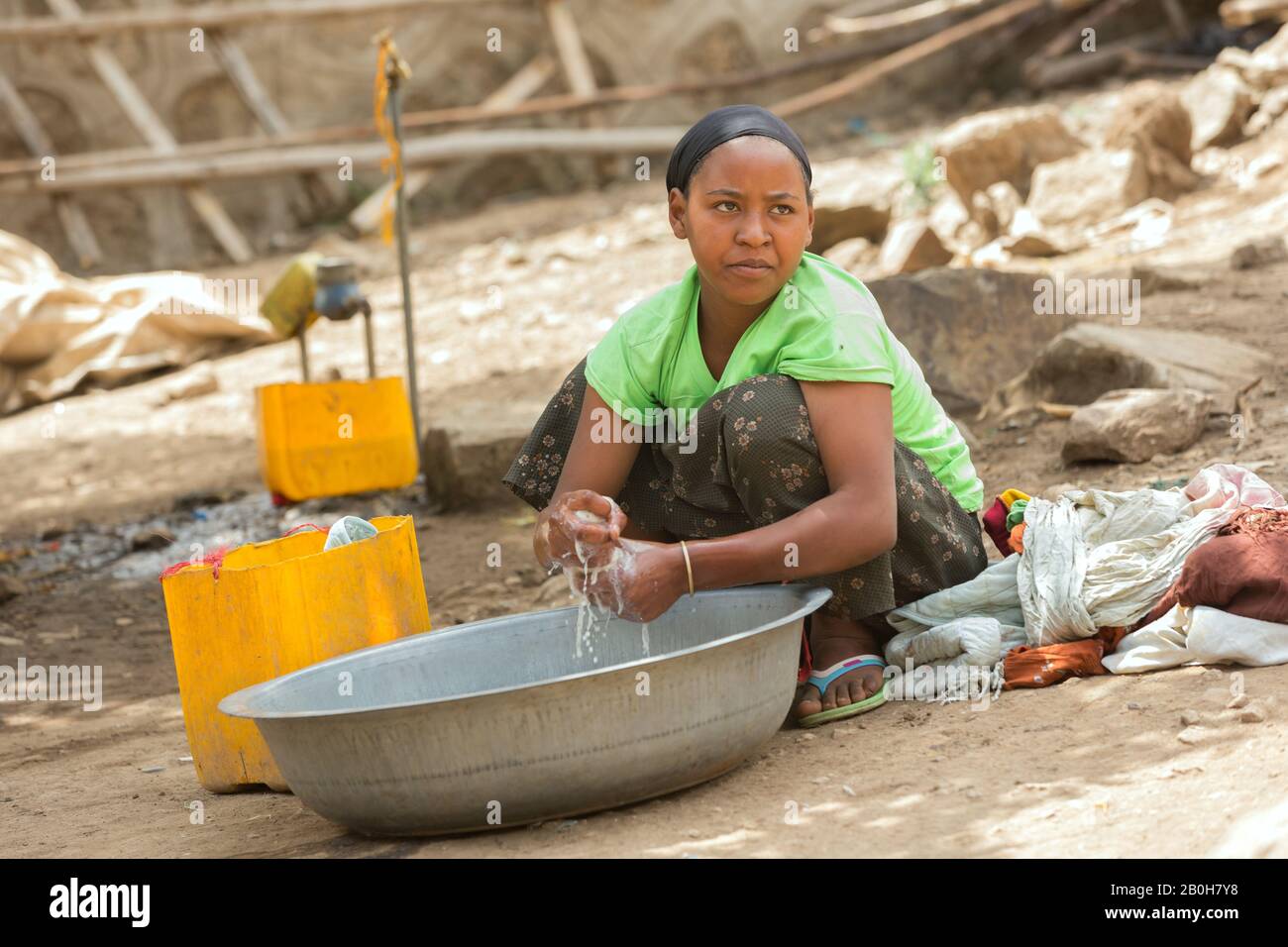07.11.2019, Adama, Oromiyaa, Ethiopia - Washerwoman. A young woman washes laundry by hand in a metal chair. Women and Migration-Prone Youth Economic E Stock Photo