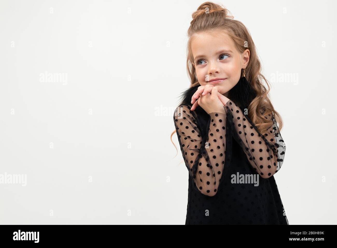 Pretty little girl in black dress stands isolated on white background ...