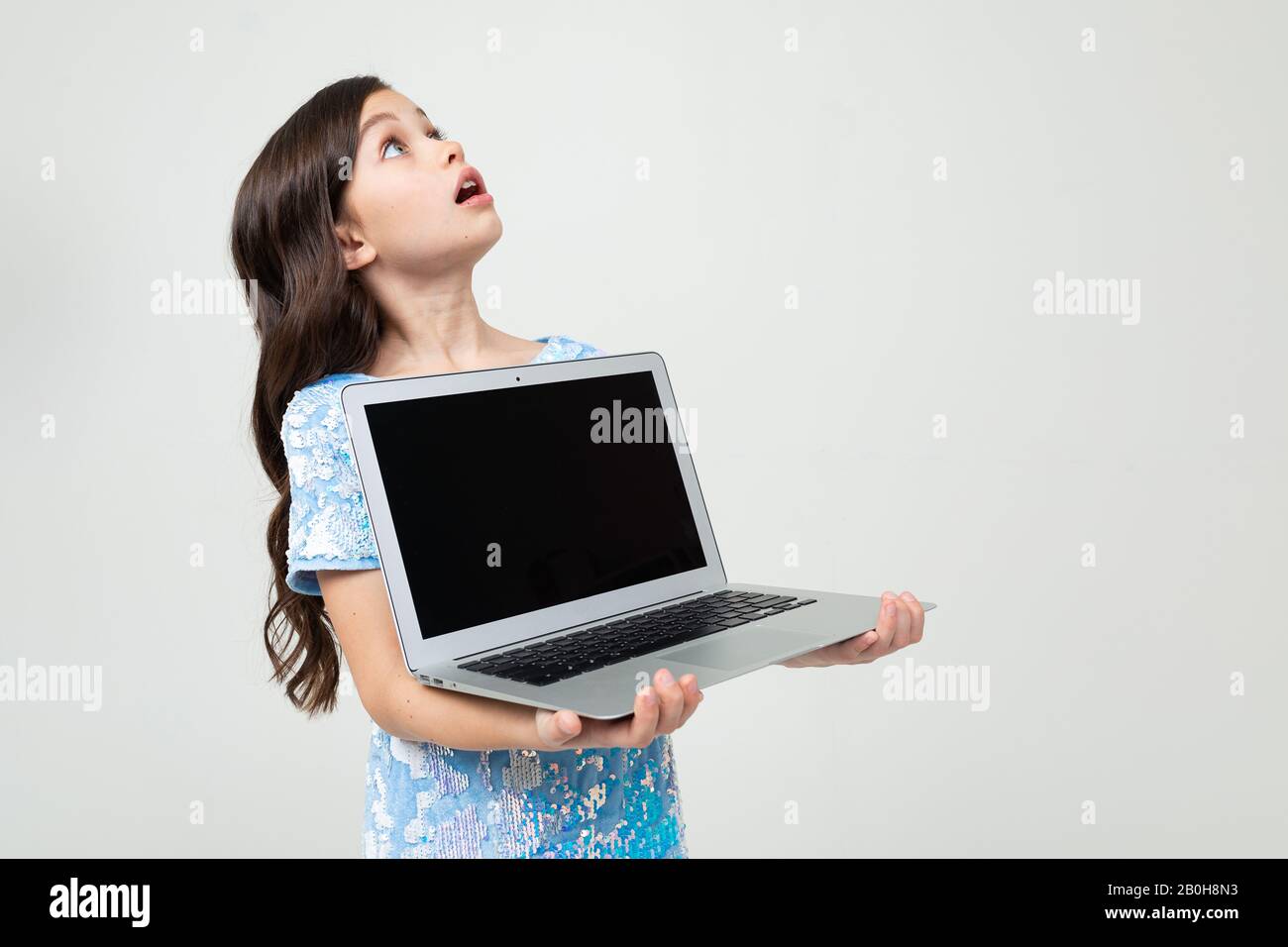 surprised teenager girl holding a laptop with a mockup for inserting a ...