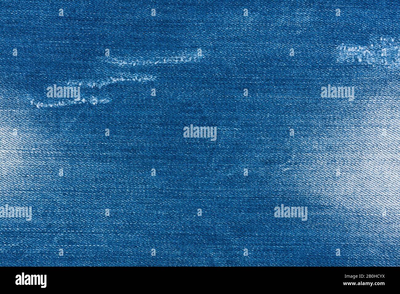 Jeans torn denim texture. Material, background. Light blue denim jeans fragment. Vintage jeans torn denim texture. Stock Photo