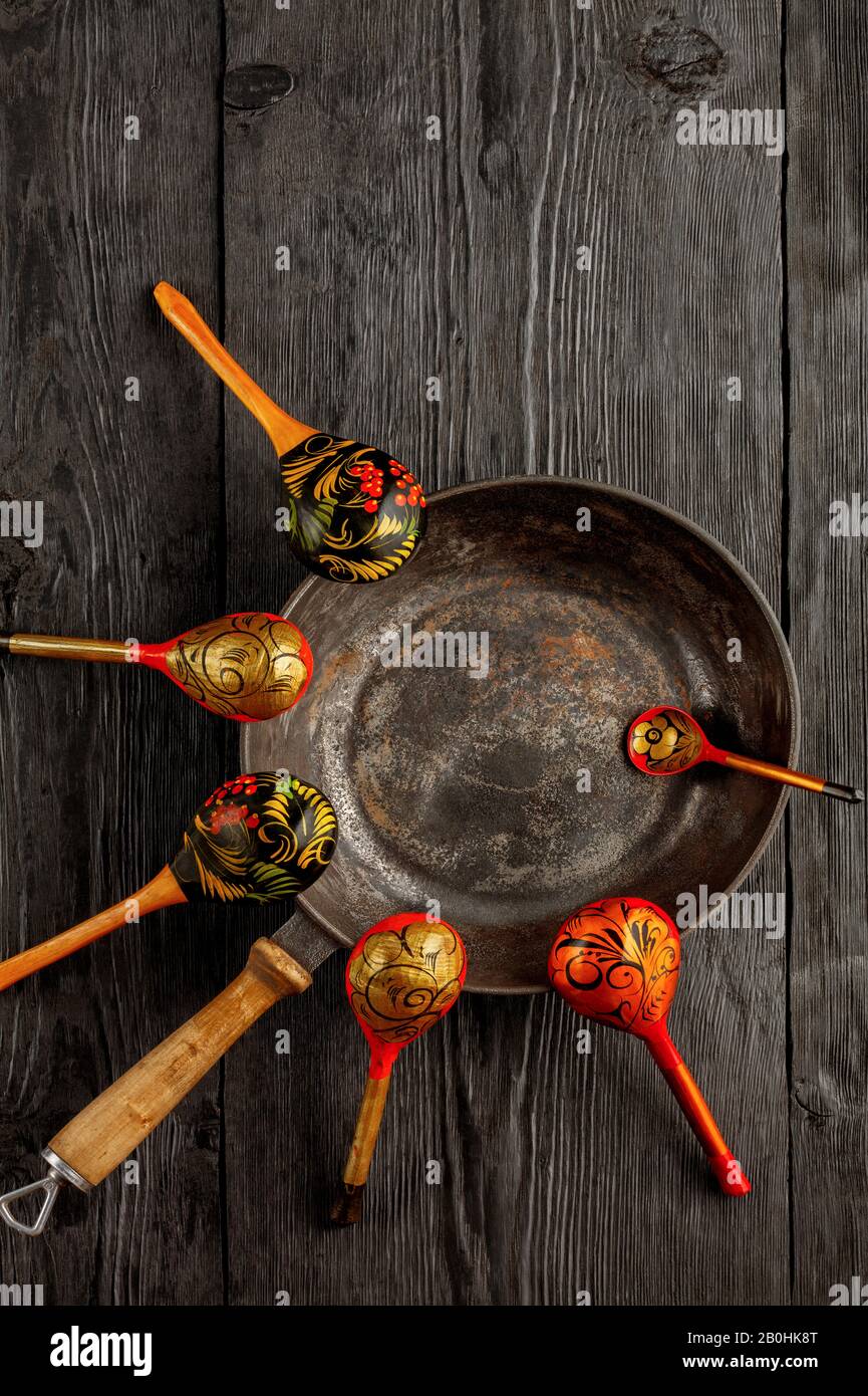 Vintage cast iron skillet and wooden old painted spoons on black rustic