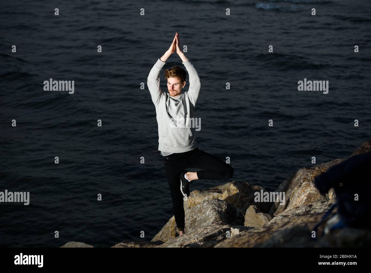 Young redhead practicing yoga, Vriksasana tree posture, to concentrate and help him with his mindfullness Stock Photo