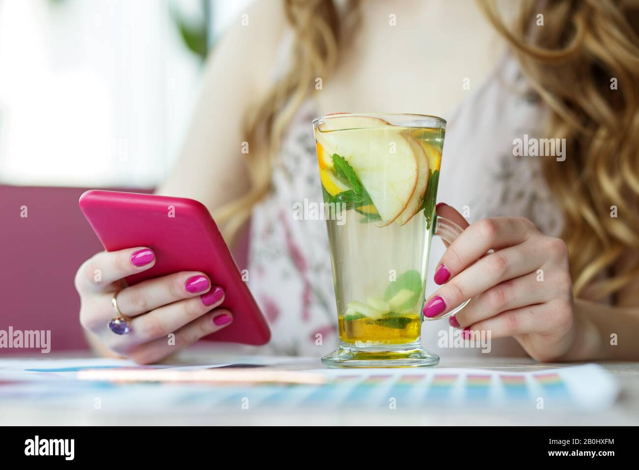 Smartphone in female hands and a delicious mocktail. The concept of ...