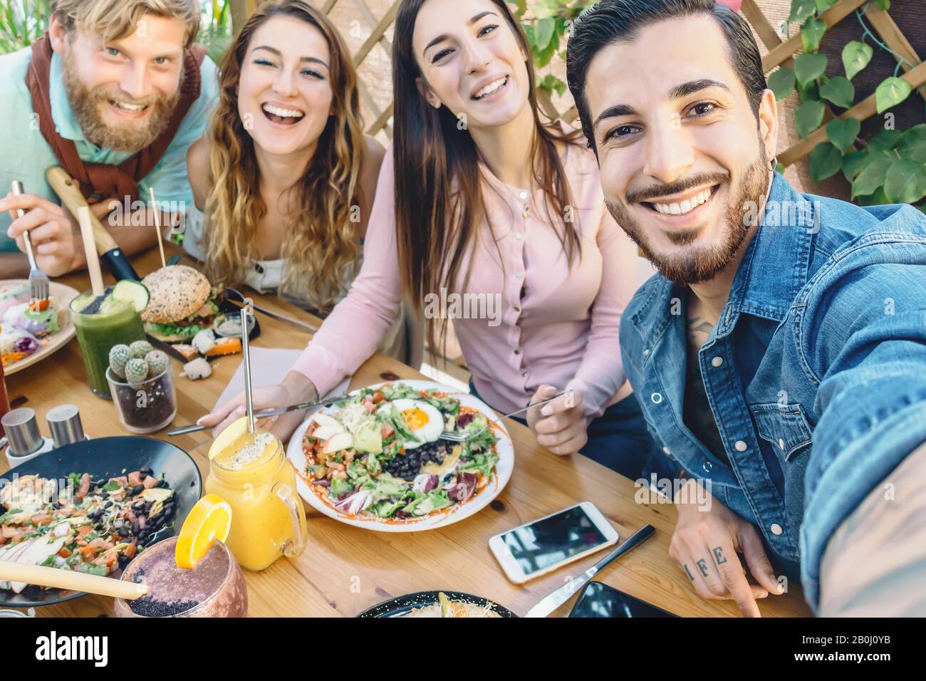 Happy friends taking selfie with mobile smartphone while lunching in coffee brunch restaurant - Young trendy people having fun eating together Stock Photo