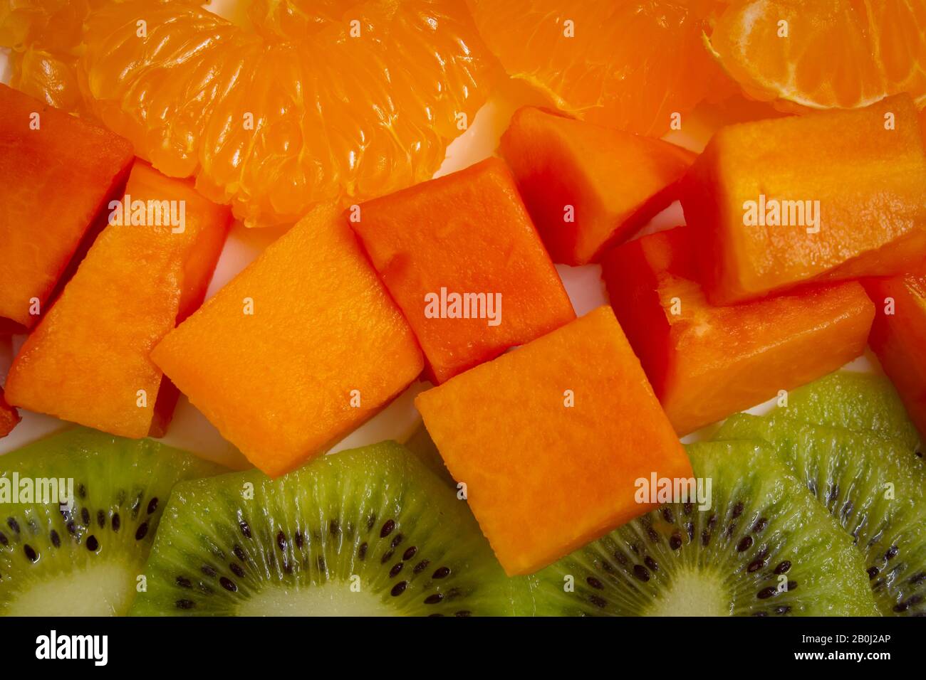 Cut and sliced kiwi, papaya and peeled oranges. Fruit platter with
