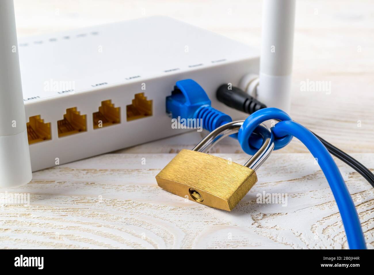 White Wi-Fi wireless router with padlock on a network cable on a white wooden  table. Forbidden or limited internet and internet censorship concepts. Stock Photo