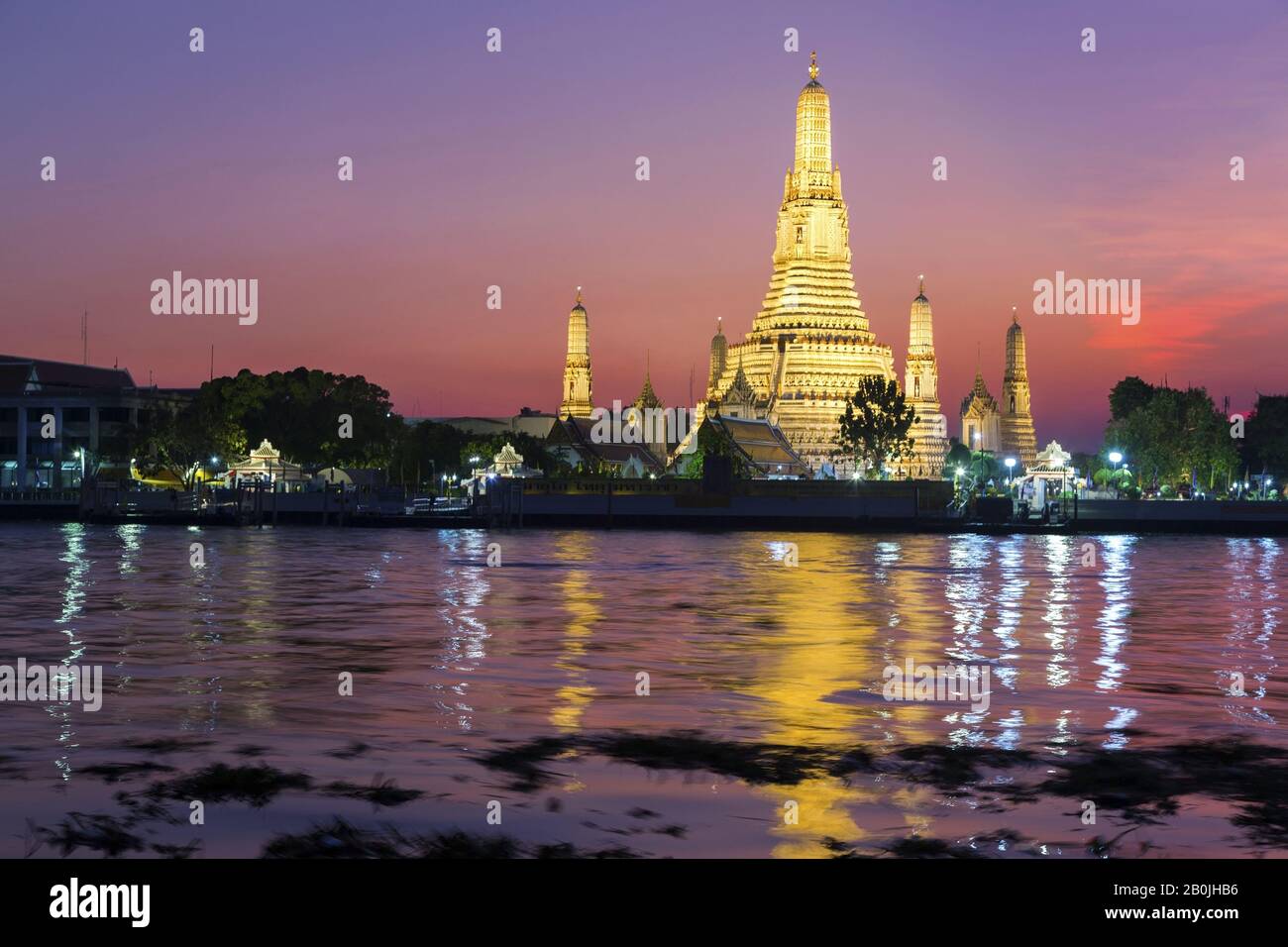 Dramatic Sunset Sky Colors over Wat Arun Temple or Temple of Dawn Buddhist Monument Reflected in Chao Phraya River in Bangkok, Thailand Stock Photo