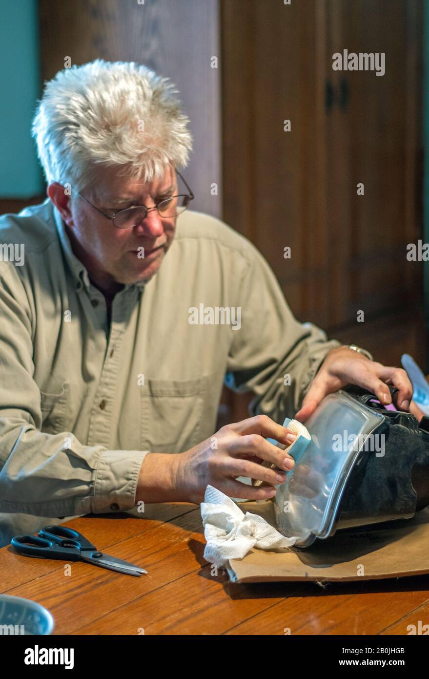 A handy man fixes a dim headlight, by sanding down the scratched up lens on the light Stock Photo