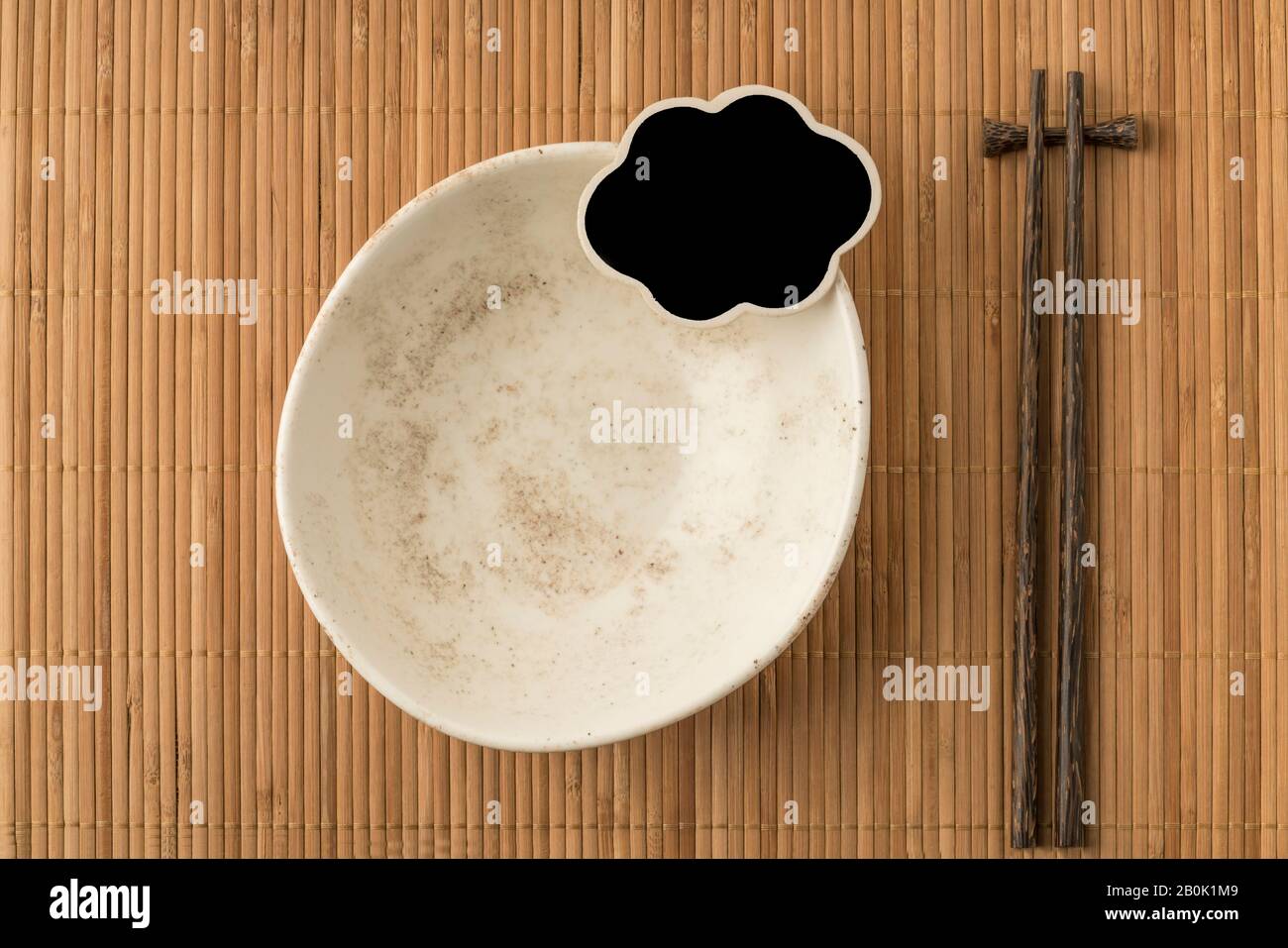an empty bowl, blank chalkboard and chopsticks on a table Stock Photo