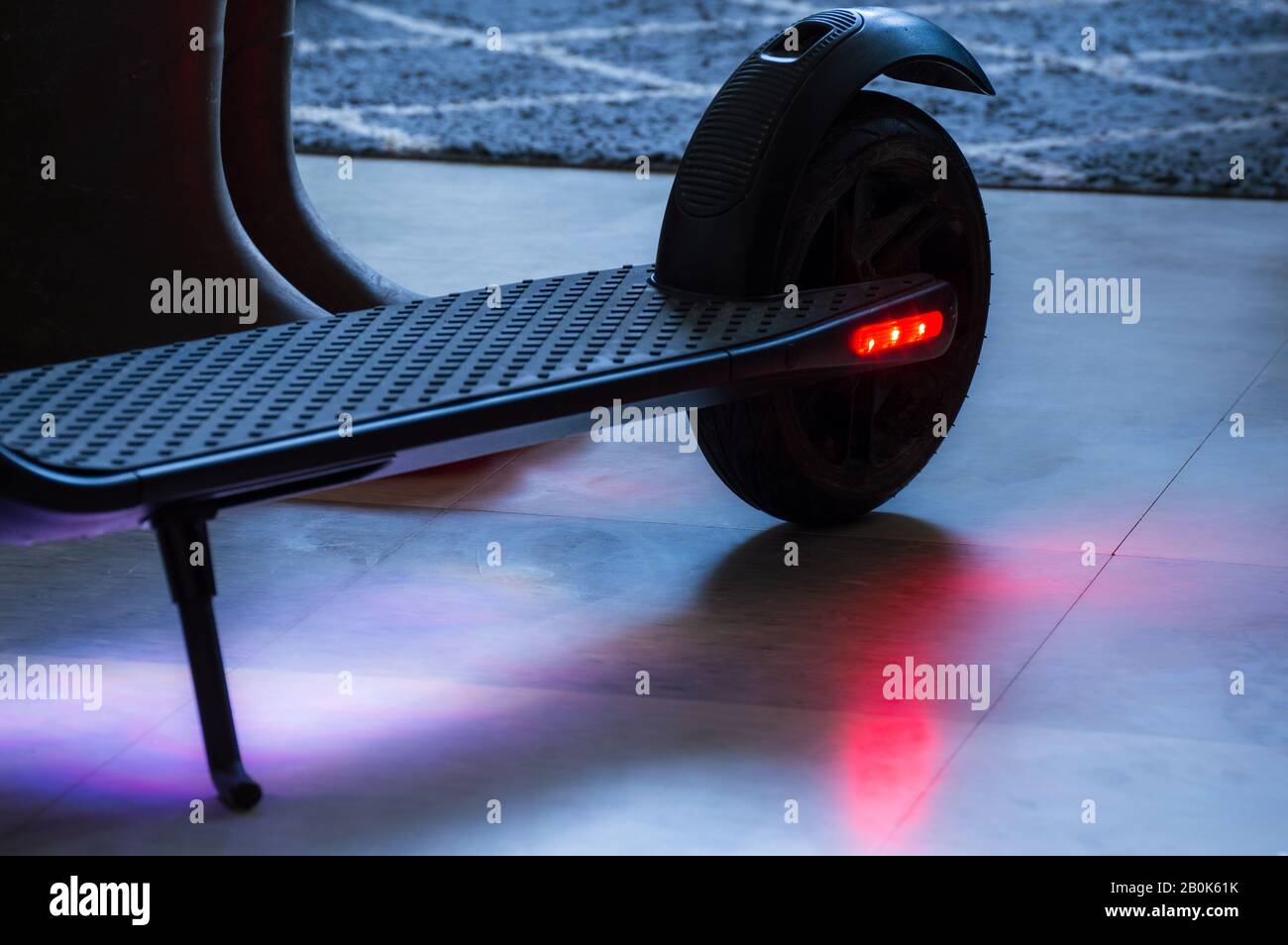 Rear wheel and brake light on an electric scooter is illuminated while recharging Stock Photo
