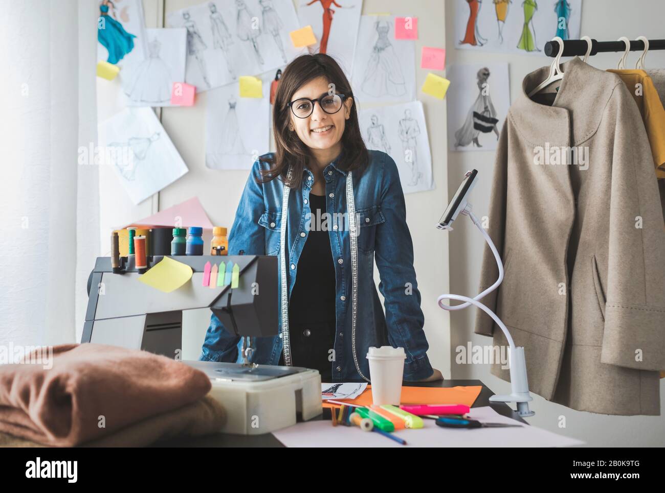 Portrait of young female fashion designer in her workshop. Young successful freelancer girl Stock Photo