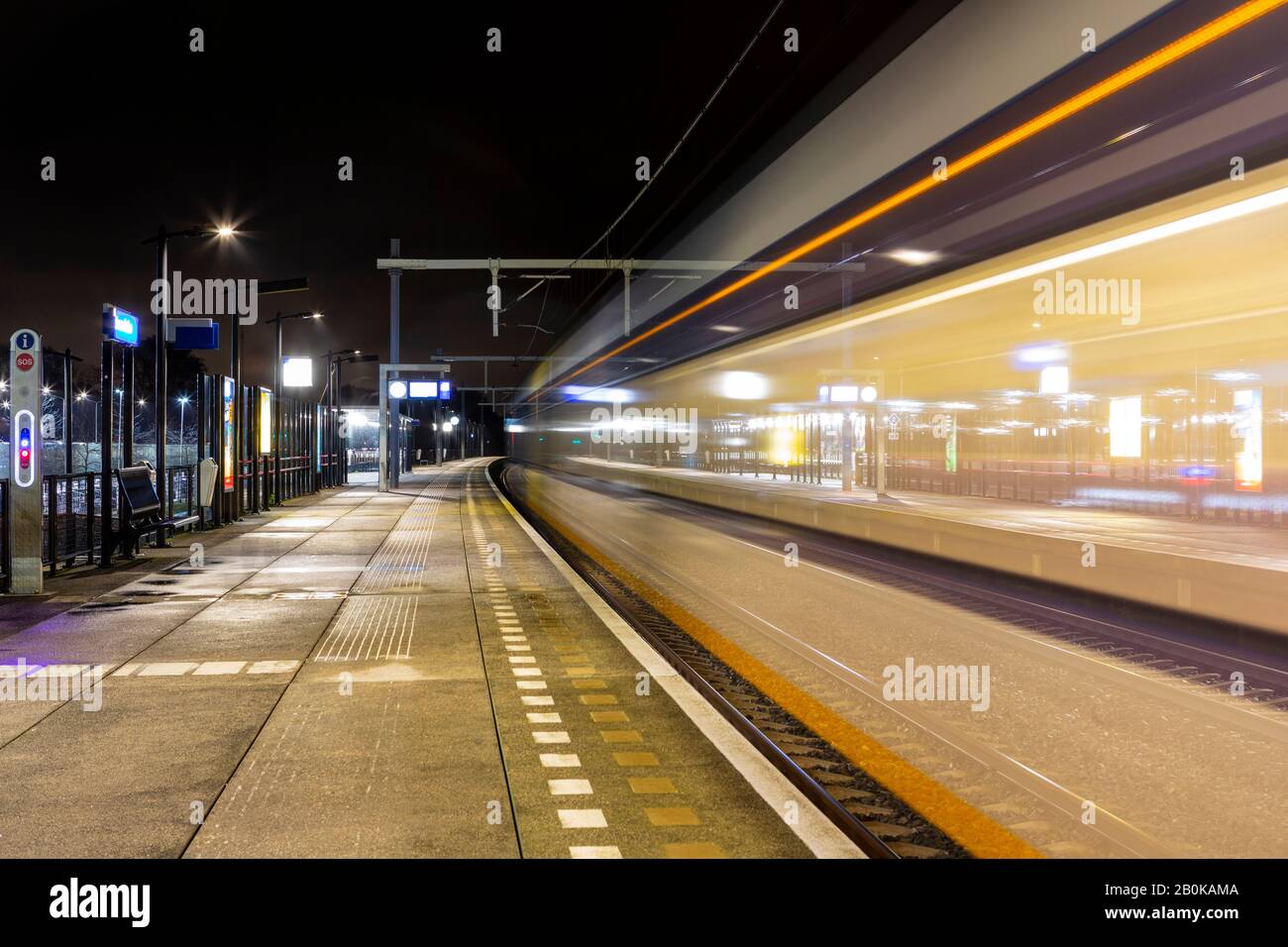 A train passes by at the train station in Sassenheim in the evening. Stock Photo