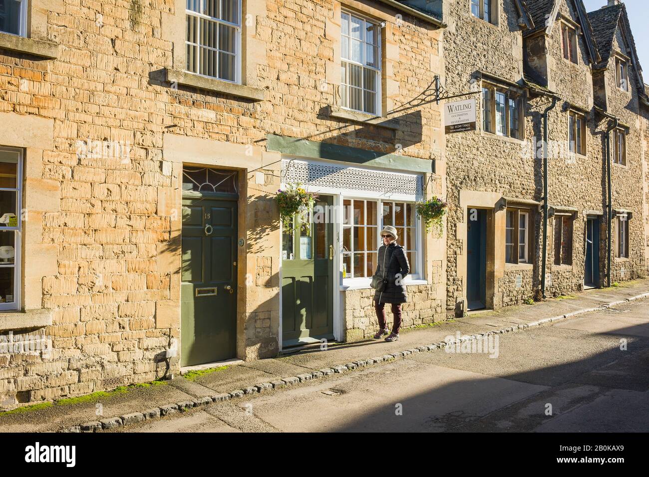 A well-dressed woman walks past a village jewellers shop in Lacock Wiltshire England UK Stock Photo