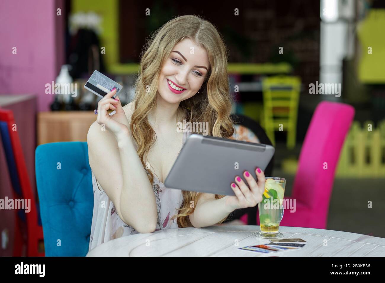 Adult smiling woman is shopping on the Internet. Big discounts. Credit card payment. Concept of e-commerce, online shopping, internet, technology and Stock Photo