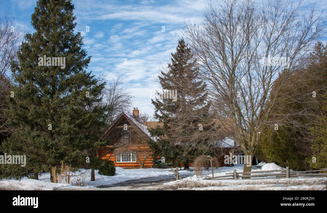 Neat wooden, timbered, farmhouse in winter against a blue sky with ...