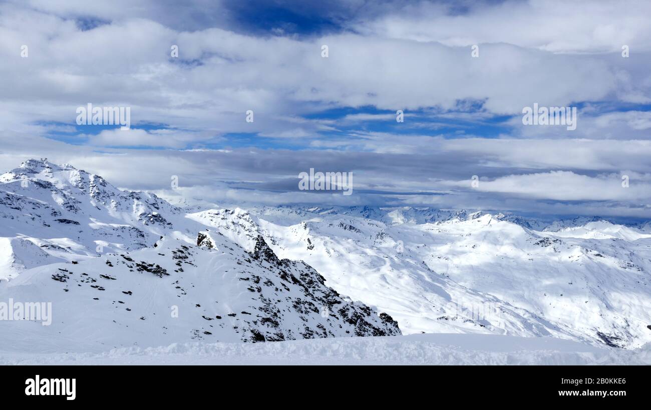 Panoramic view of alpine peaks covered with snow under low clouds, 3 Valleys Val Thorens winter resort, Alps, France . Stock Photo