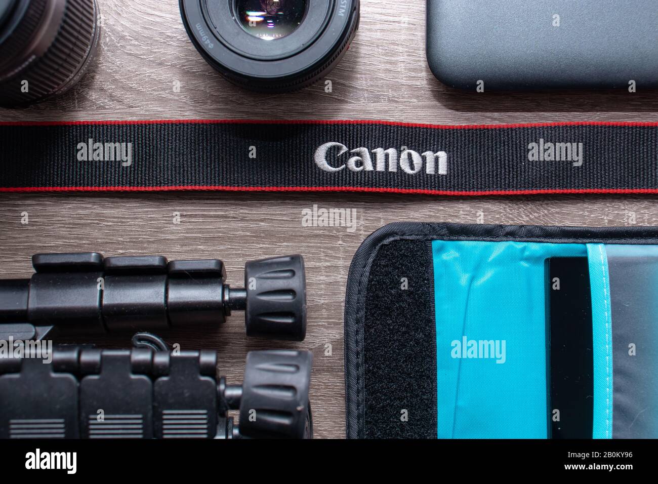Photography flat lay on a grey wood table. Canon black strap with red  stripes in focus. Canon lenses, canon camera gear Stock Photo - Alamy