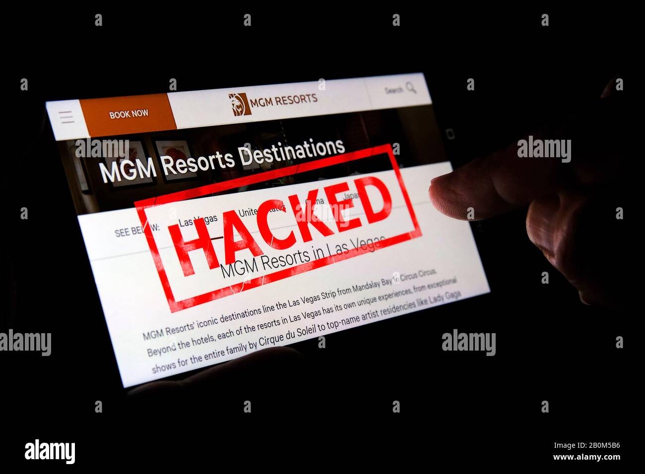 MGM website on the smartphone screen with a red stamp HACKED on top and finger pointing at it. Concept. Editorial illustrative. Stock Photo