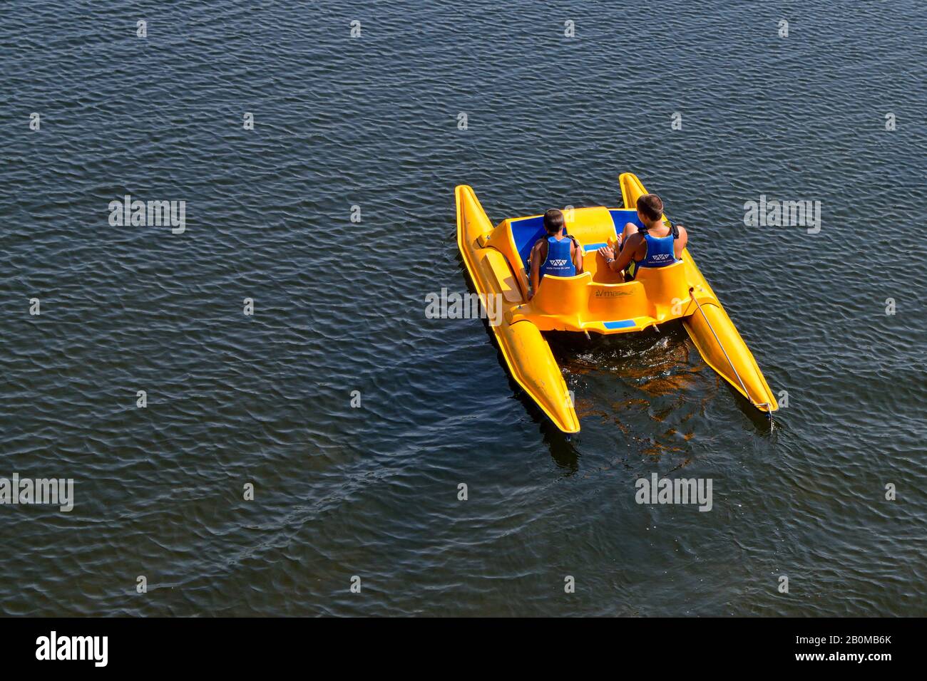 Ponte de lima river in Portugal two kids on pedaling boat having fun at summer. Kids on boats with safety water gear vests. Brothers together. Stock Photo