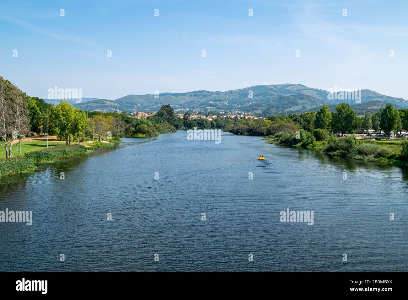Ponte de lima river in Portugal landscape with pedaling boat passing, people enjoying nautical activities on summer. Ponte de Lima landscape view. Aereal Stock Photo