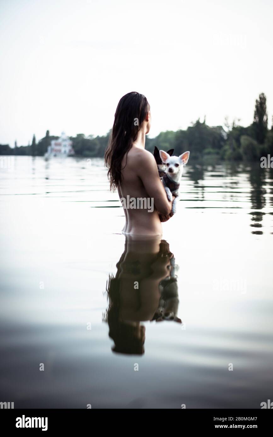 strong beautiful woman holds two small dogs in natural berlin lake Stock Photo