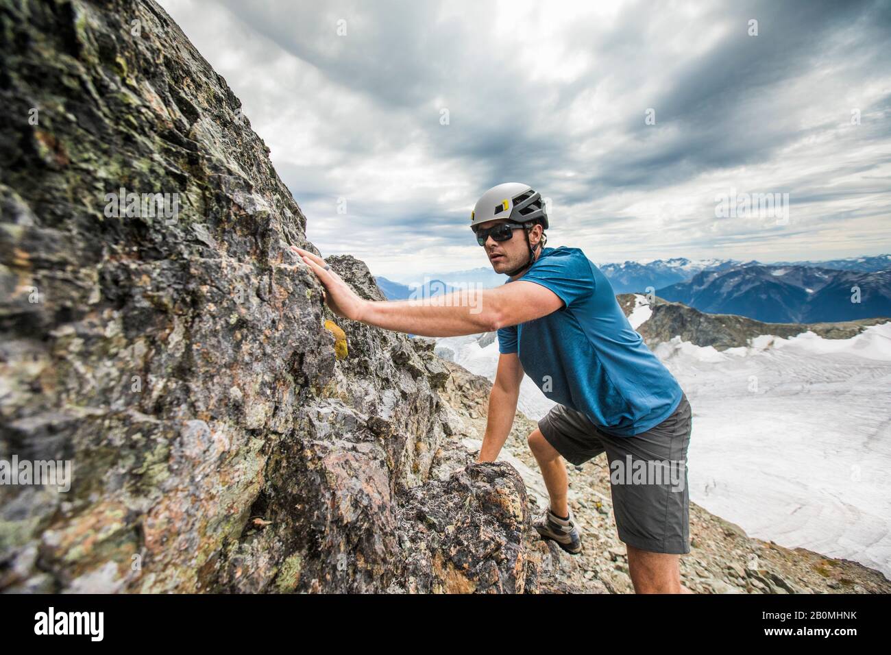 Side view of climber scrambling up toward mountain summit. Stock Photo