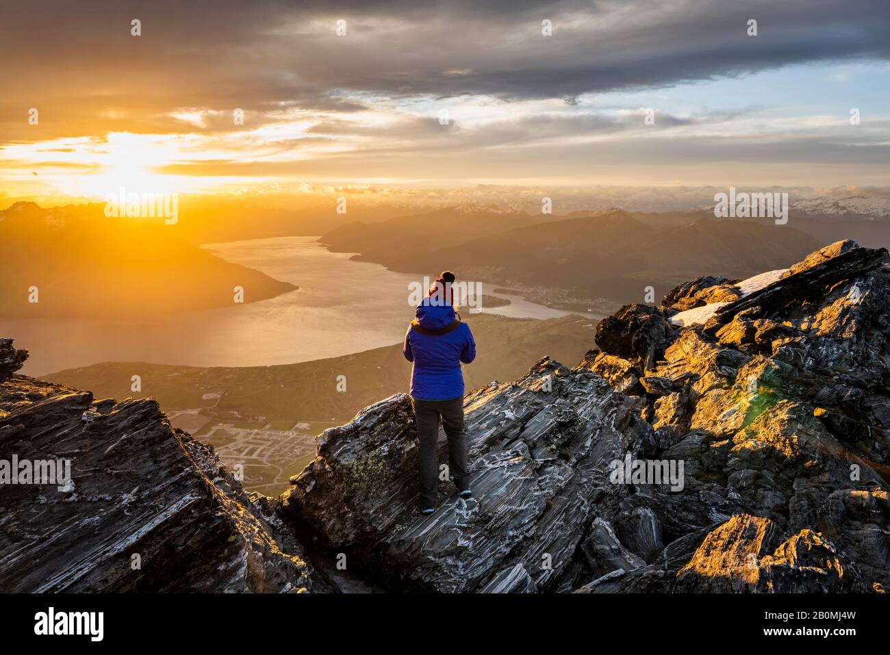 figure at sunset above Queenstown and lake, Remarkables New Zeala Stock ...