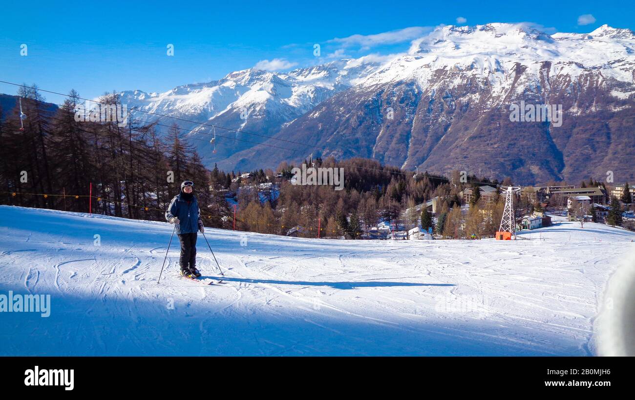 Mountain landscape with winter snow and people enjoy skiing under blue sky, Italy Stock Photo