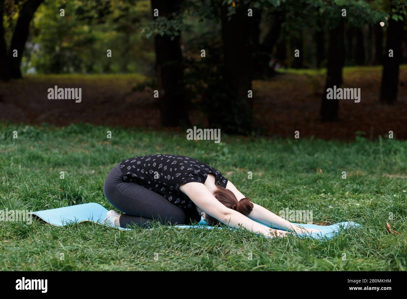The relaxed girl is doing yoga in the park on carpet Stock Photo Alamy