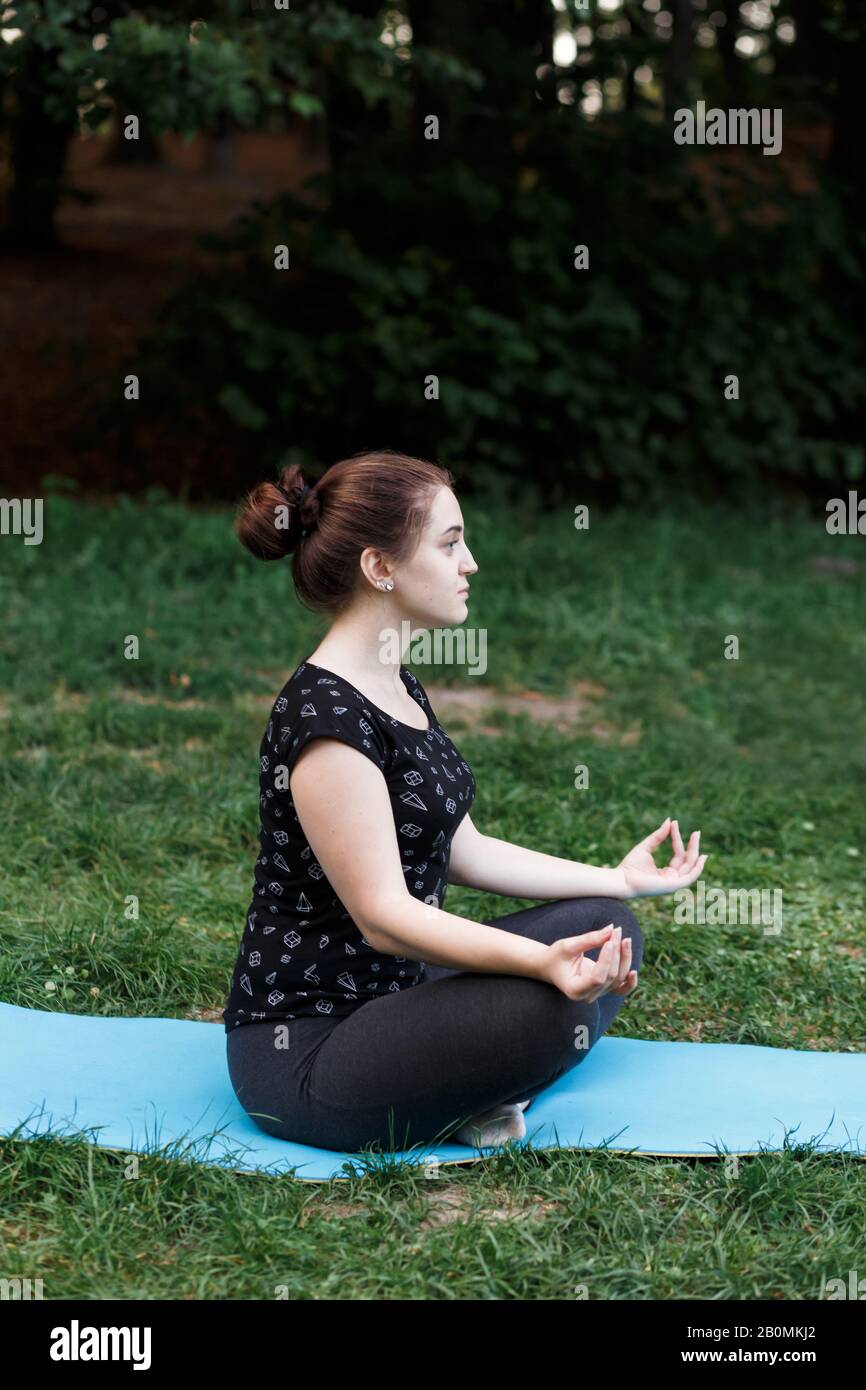 The relaxed girl is doing yoga in the park on carpet Stock Photo