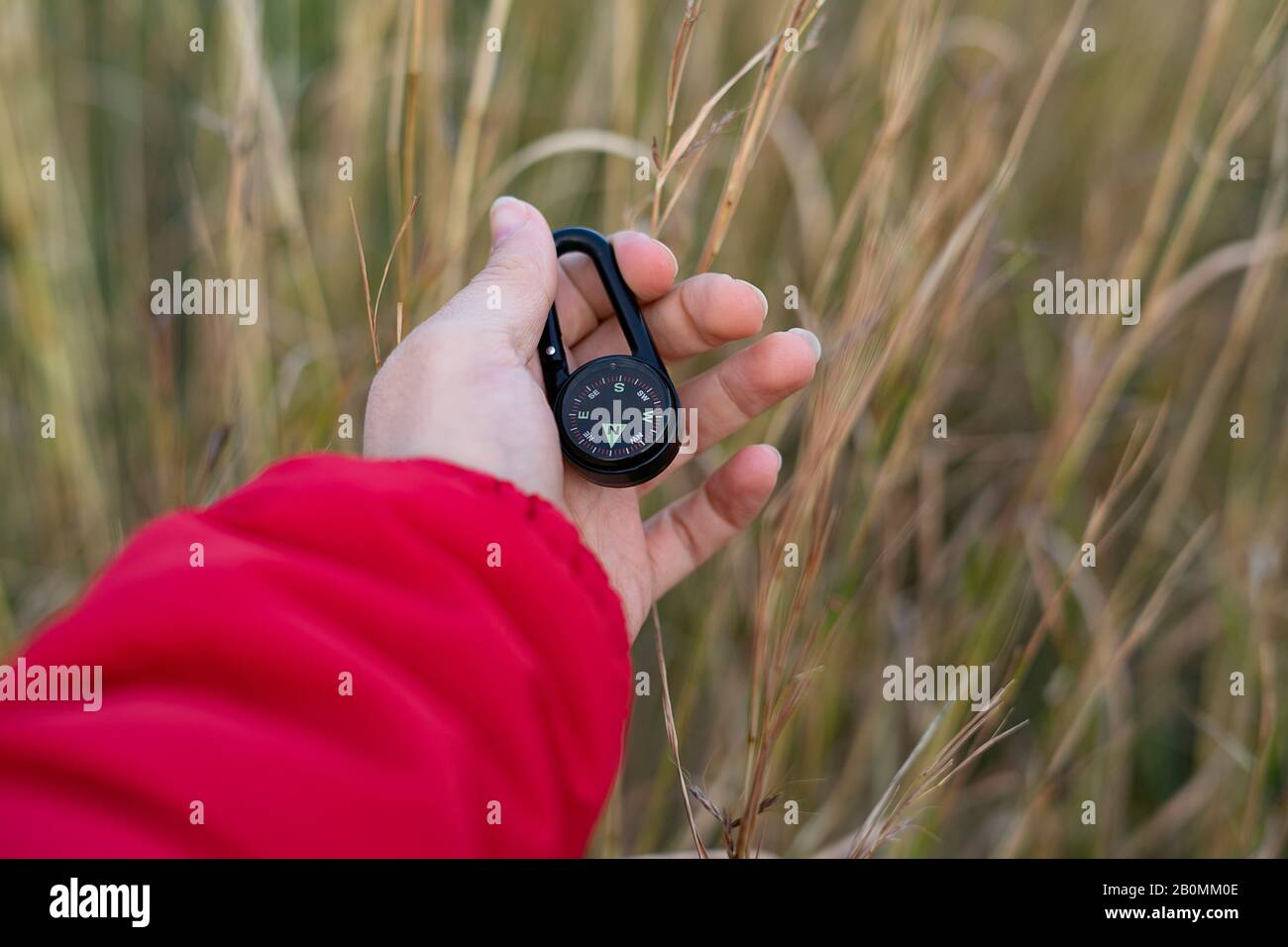 Hand picking up a black compass in the woods. Concept of compass and
