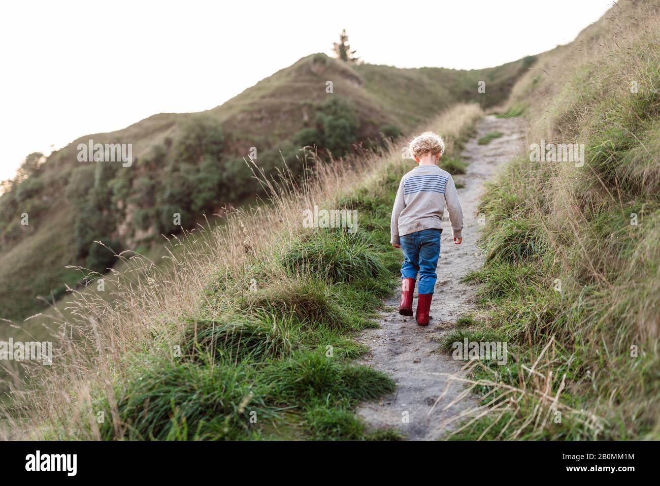 Preschool aged child walking on hillside path Stock Photo