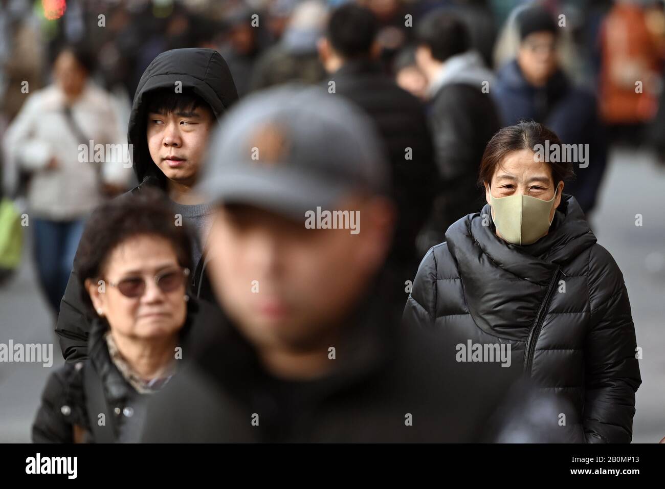 New York, USA. 20th Feb 2020. A woman wears a protective mask as she walks in the Flushing section of the New York City borough of Queens, NY, on February 20, 2020. The World Health Organization has declared a global public health emergency as cases of the deadly new coronavirus COVID-19 infections climb over 75,000 worldwide and reported deaths exceed 2000. (Anthony Behar/Sipa USA) Credit: Sipa USA/Alamy Live News Stock Photo