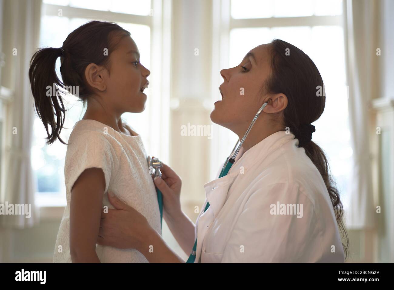 Young girl for check-up at the doctor who is using a stethoscope to ...