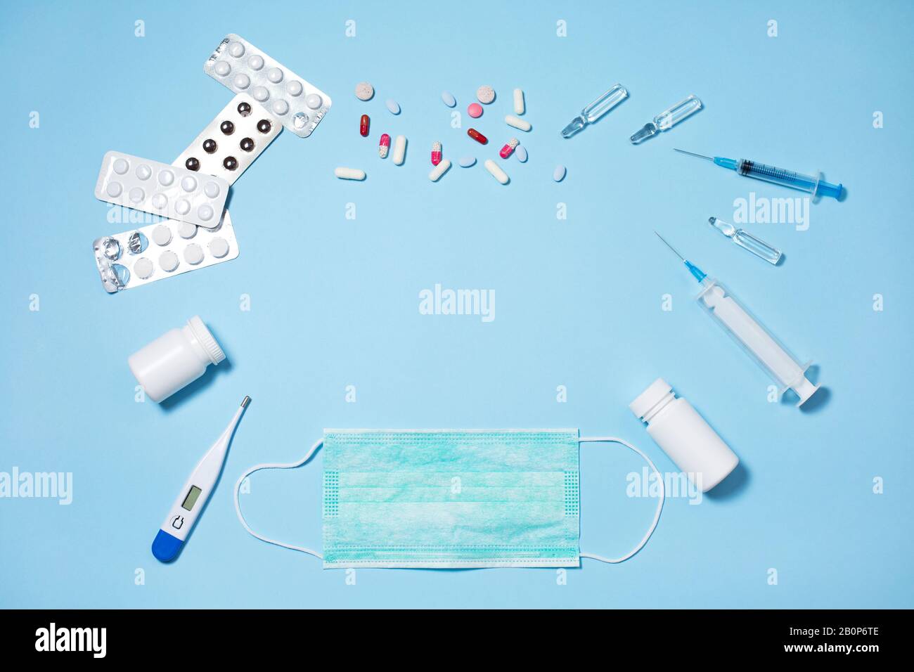 Medical pills and capsules in packs, an injector syringe on blue ...