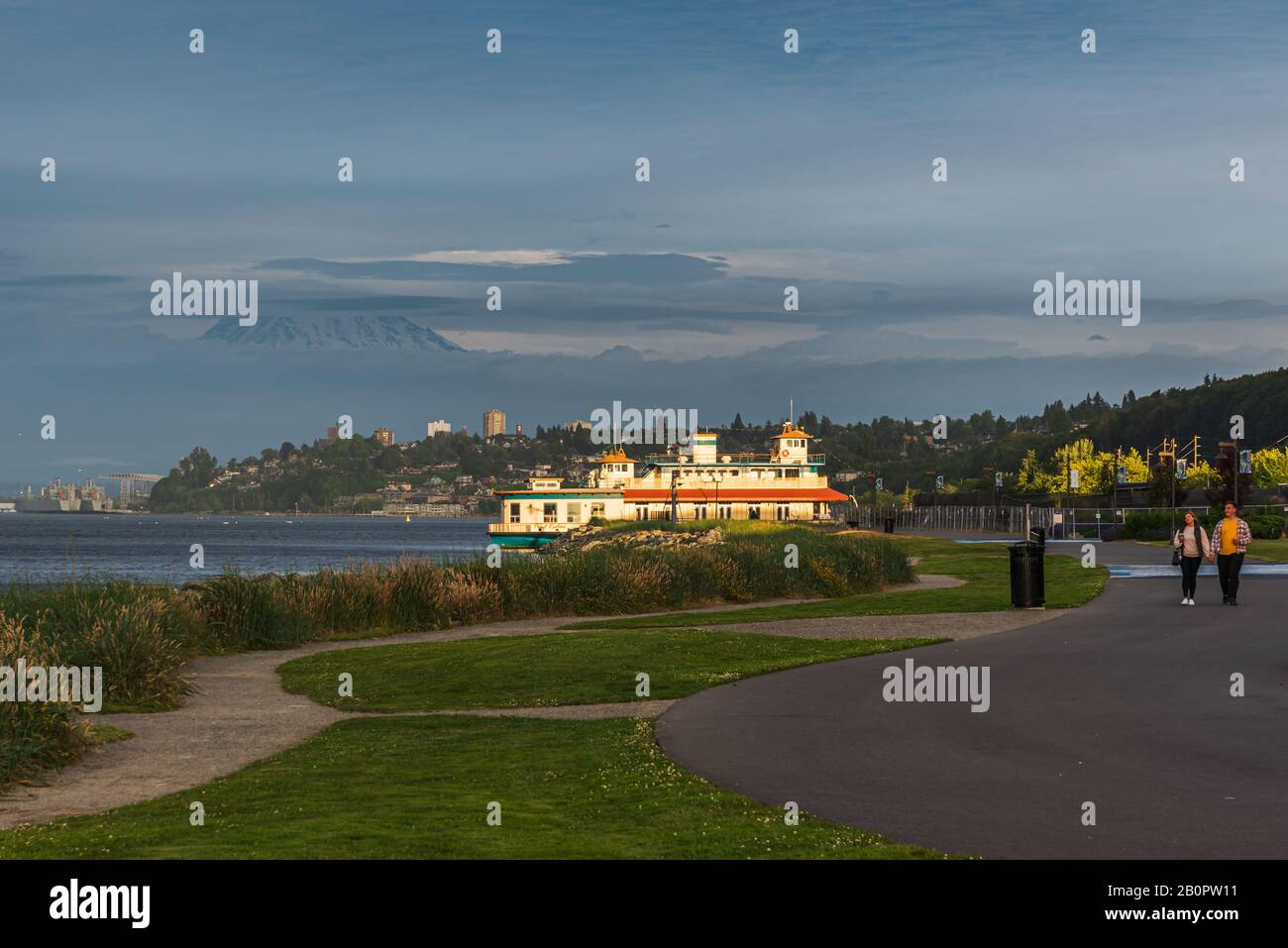 Mt Rainier Hovers Over Downtown Tacoma and Commencement Bay as Seen from Point Ruston with people walking and Riding Bikes Stock Photo