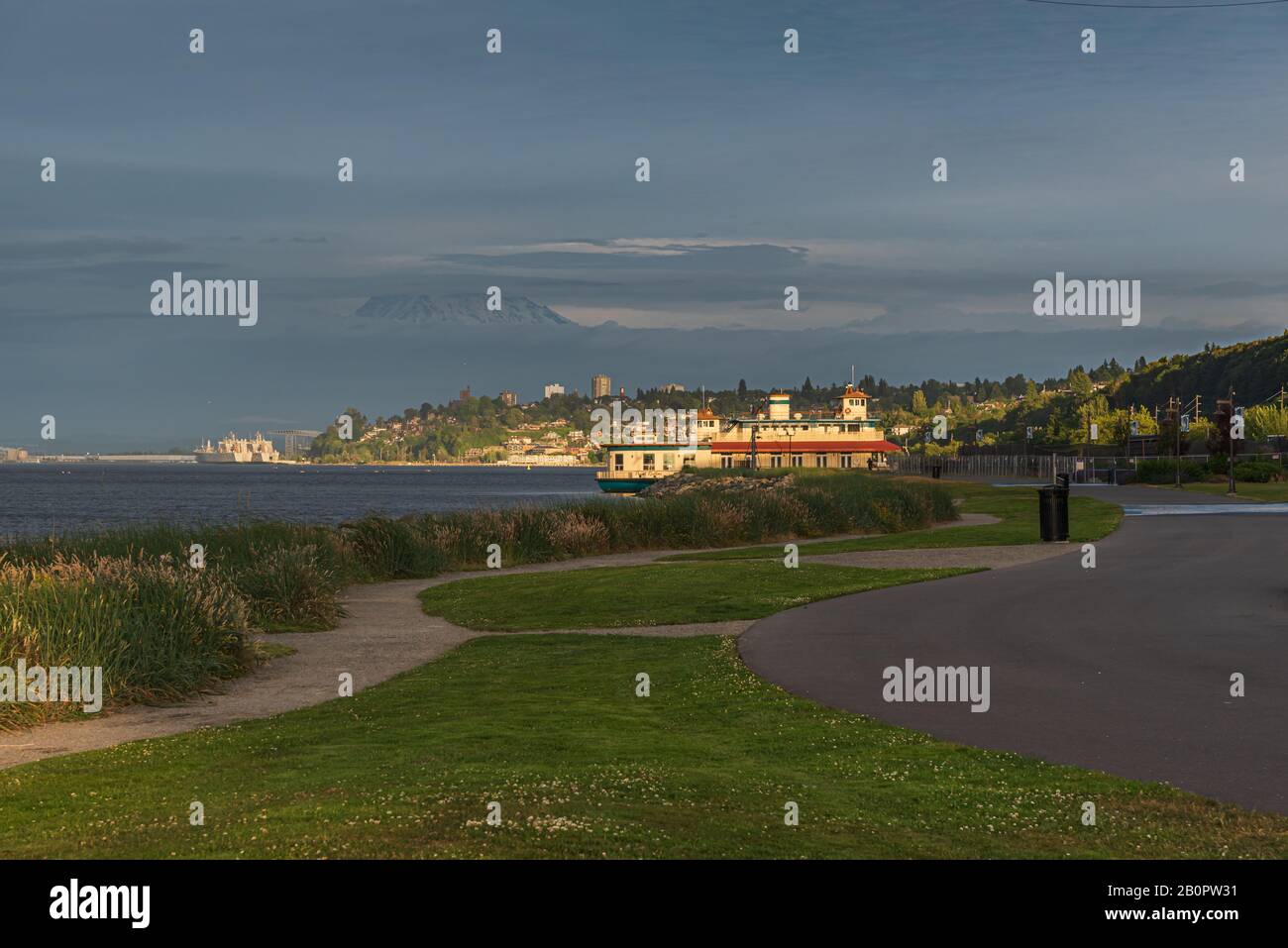 Mt Rainier Hovers Over Downtown Tacoma and Commencement Bay as Seen from Point Ruston with people walking and Riding Bikes Stock Photo
