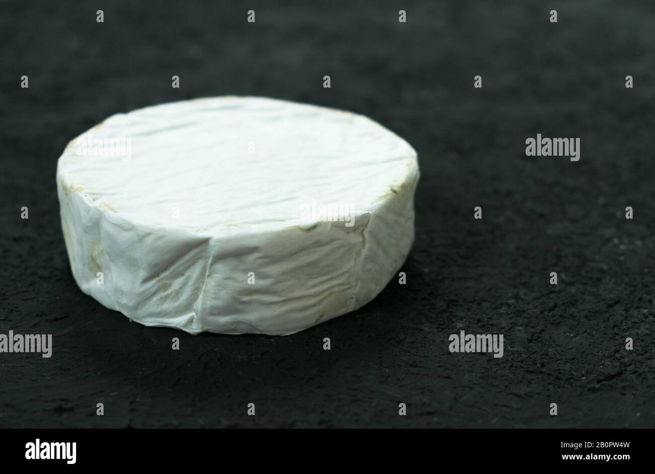A whole head of Camembert cheese on a black background. Copy space. Stock Photo