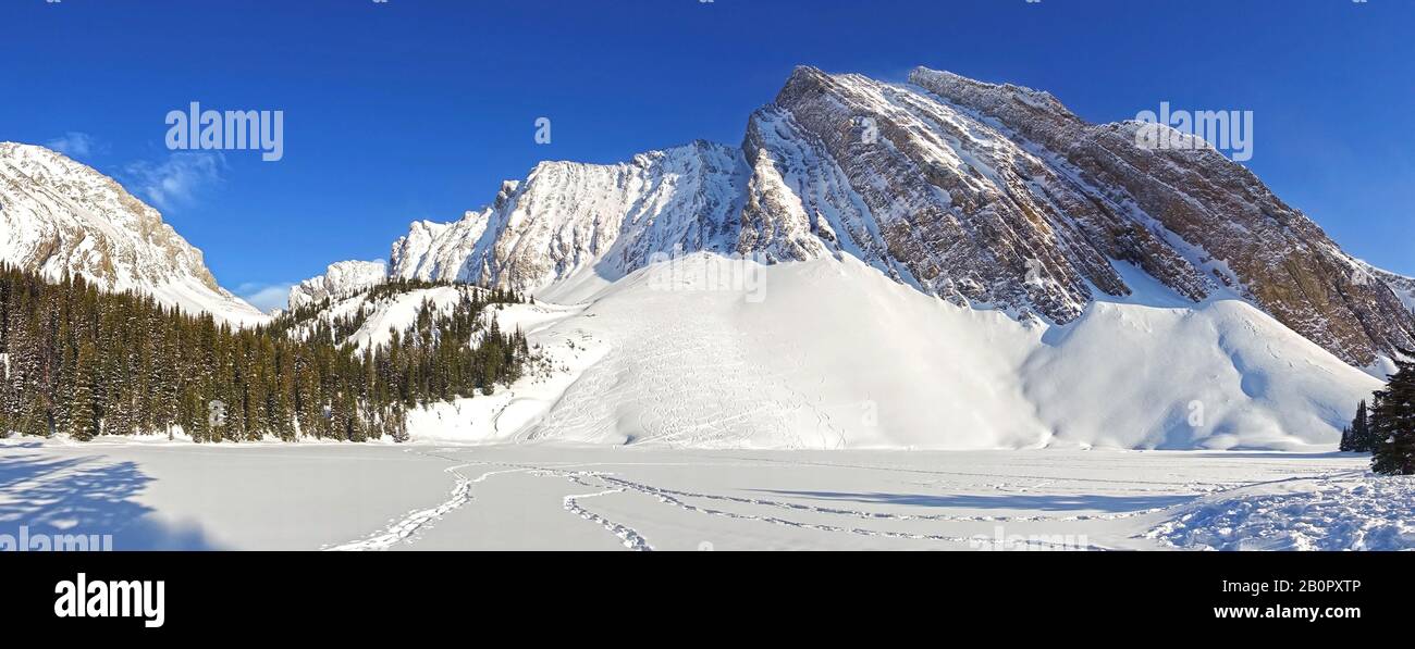Wide Panoramic Winter Landscape of Jagged Mountain Peaks above Frozen Snow Covered Chester Lake, Kananaskis Country Rocky Mountains Alberta Canada Stock Photo