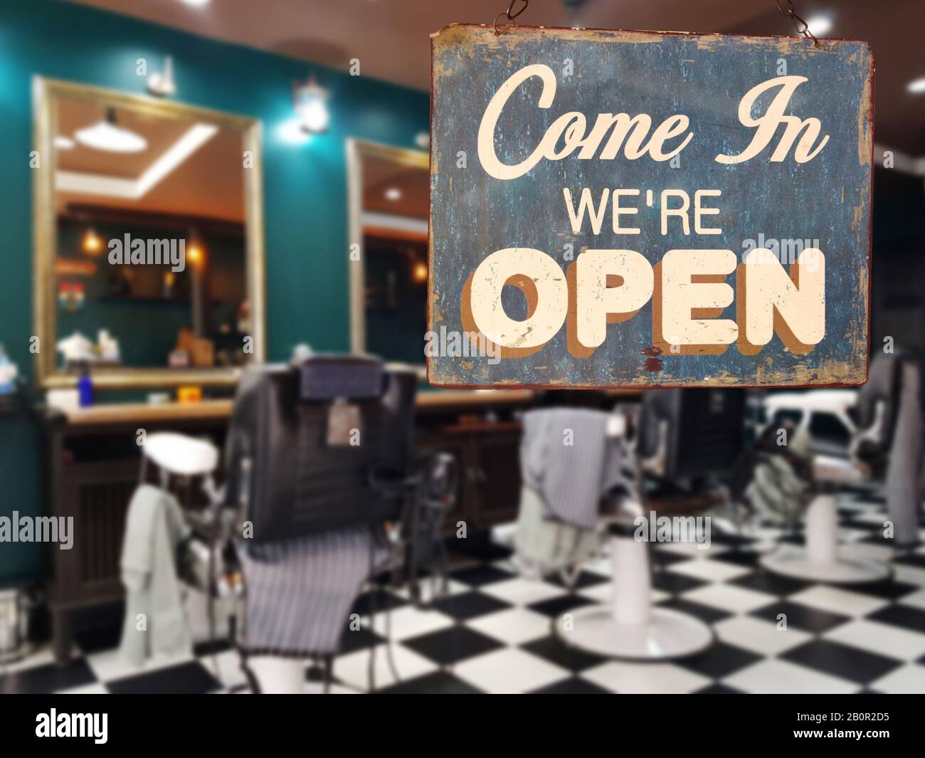 a business vintage sign that says 'Come in We're Open' on barber and hair salon shop window. image of abstract blur barber and hair salon shop Stock Photo