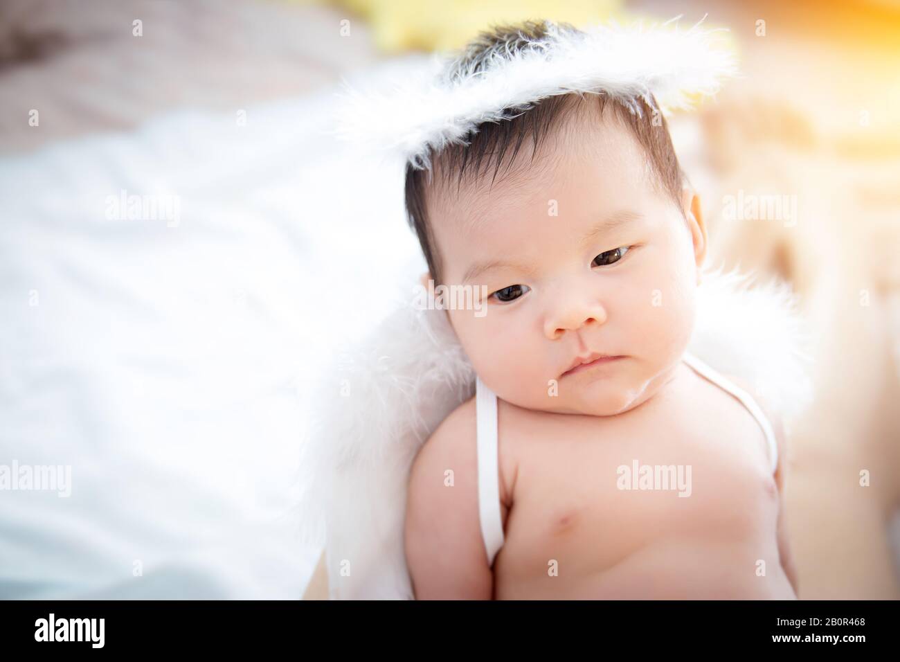 Close-up beautiful newborn baby girl. A portrait of a beautiful newborn baby girl wearing angel wings and angel ring. Stock Photo