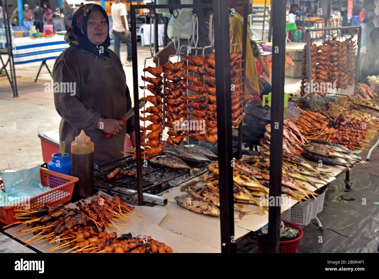 Woman sells barbecue chicken wings and fish on sticks, Ramadan Night Food Market and Bazaar, Kota Kinabalu, Sabah, Borneo, Malaysia Stock Photo