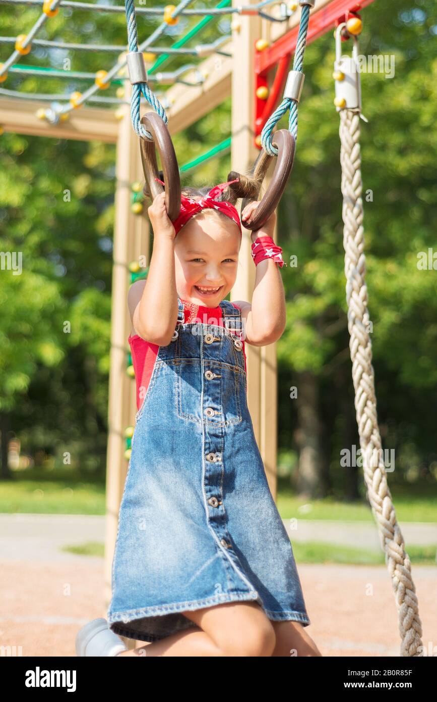 Kids Using Playground Rings ittle girl playing on the playground. the child hung on the gymnastic ...
