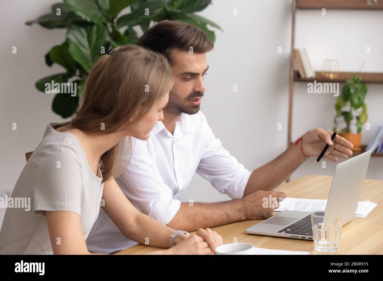 Businessman, mentor and trainee working on online project together, using laptop, looking at screen, colleagues discussing results, ideas, coach helpi Stock Photo